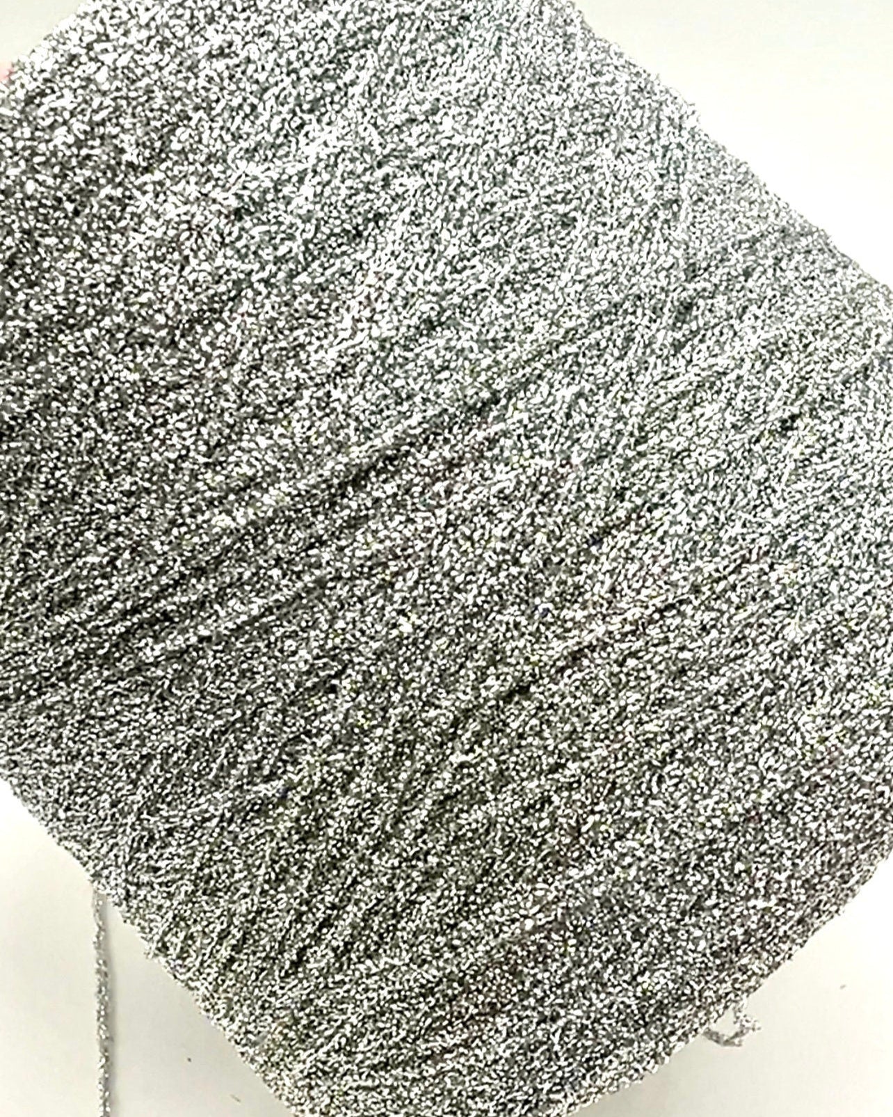 Close-up of a ball of silver glittery yarn on a white background