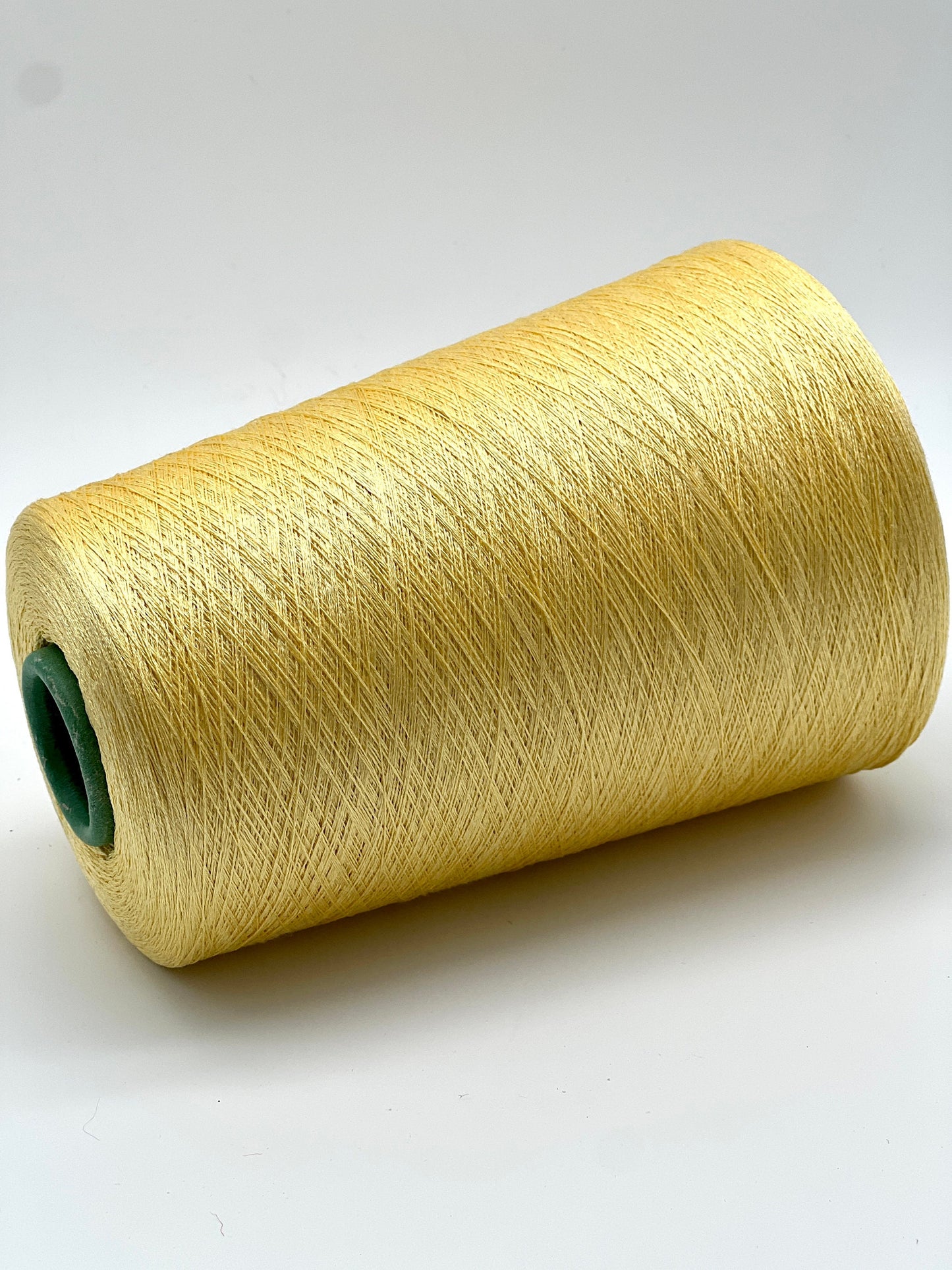 Spool of yellow thread on a white background