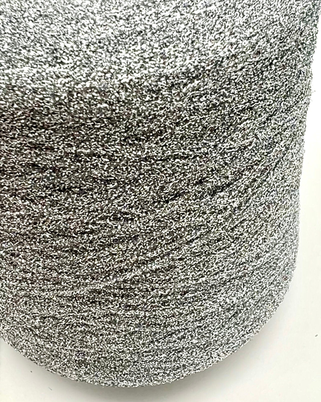 Spool of silver glittery yarn on a white background