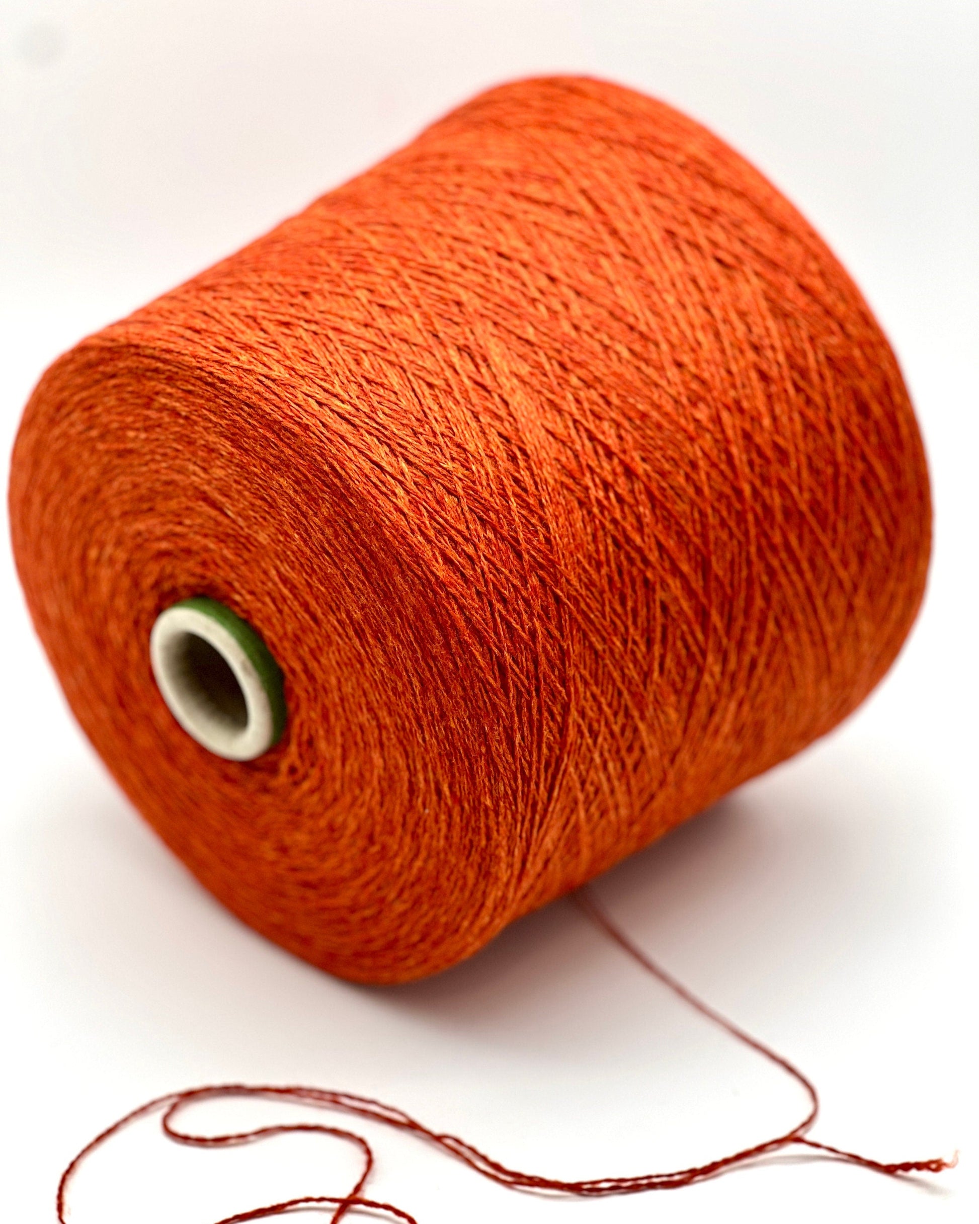 Spool of orange thread on a white background