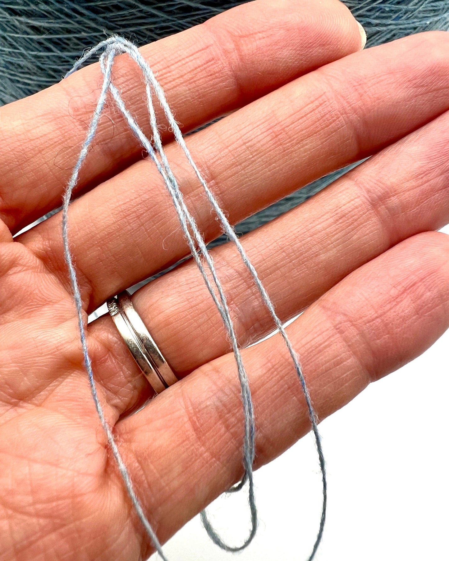 Thin metal wire held between fingers with a blurred background