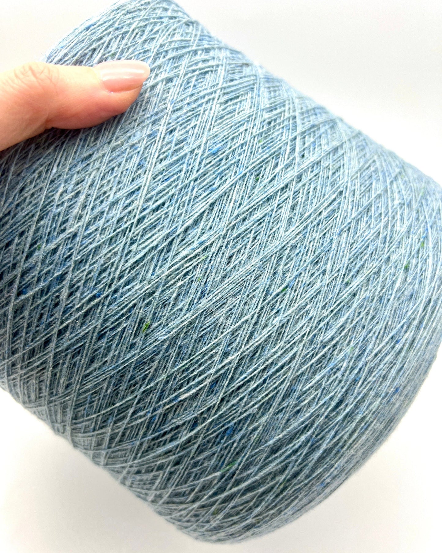 Blue skein of yarn held by a hand on a white background