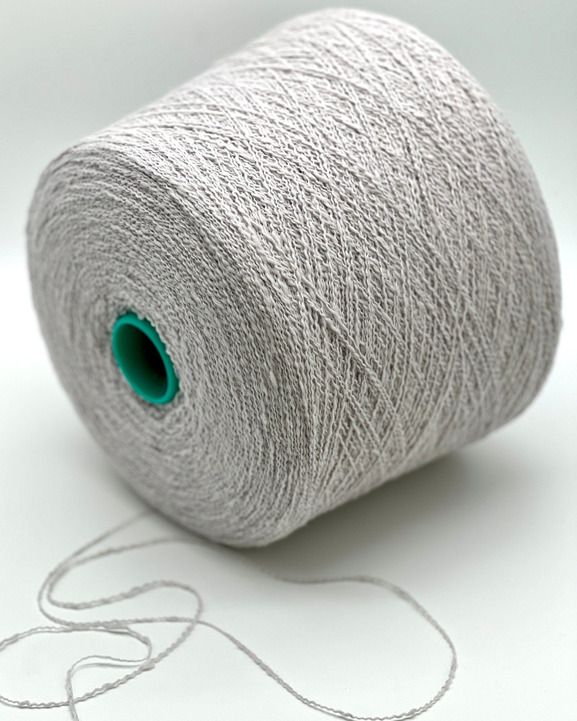 Spool of gray yarn with a green core on a white background