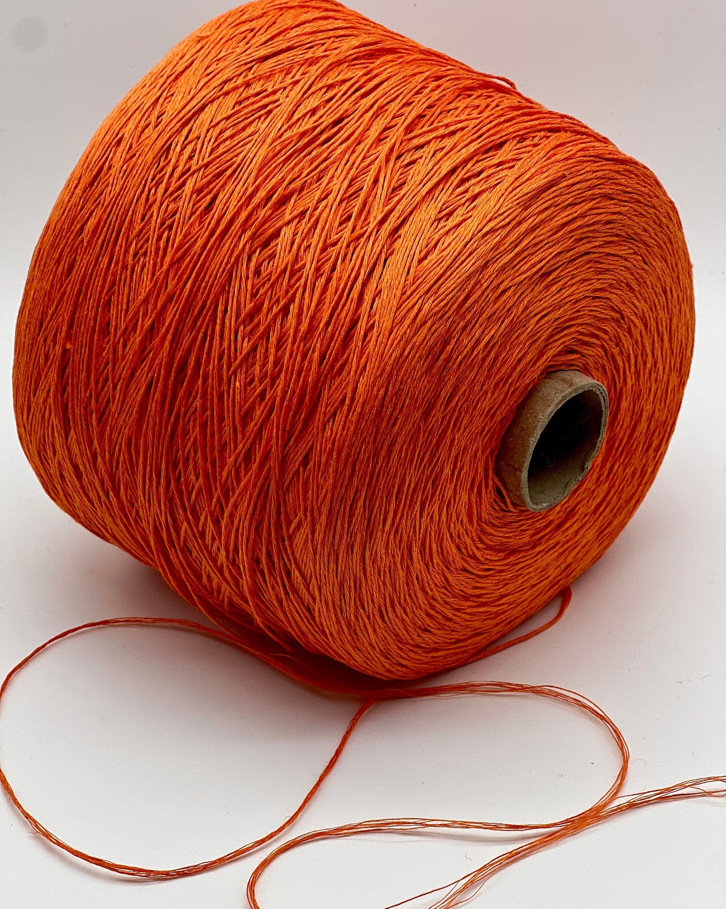 Spool of orange thread on a white background