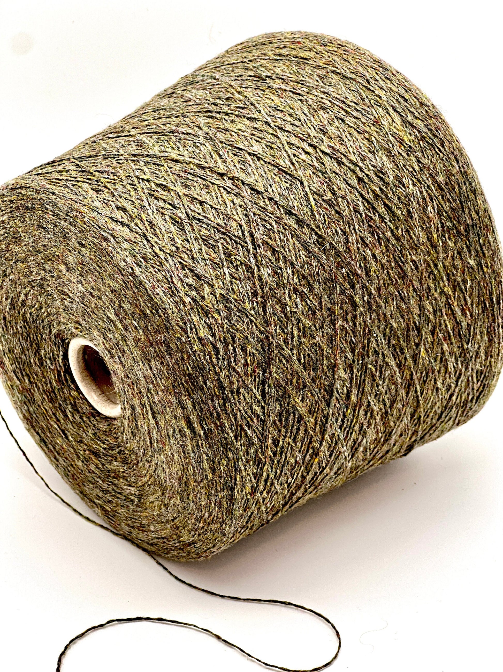 Spool of green yarn on a white background