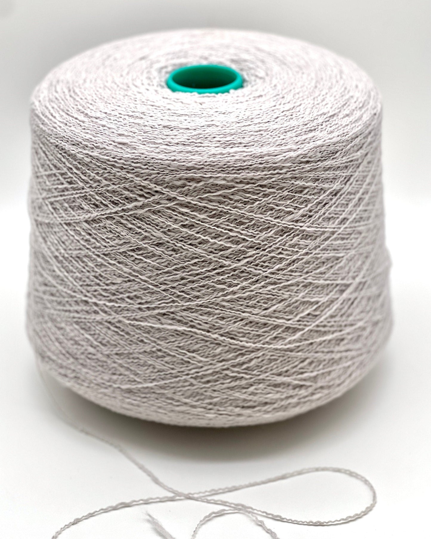 Spool of white yarn on a light gray background