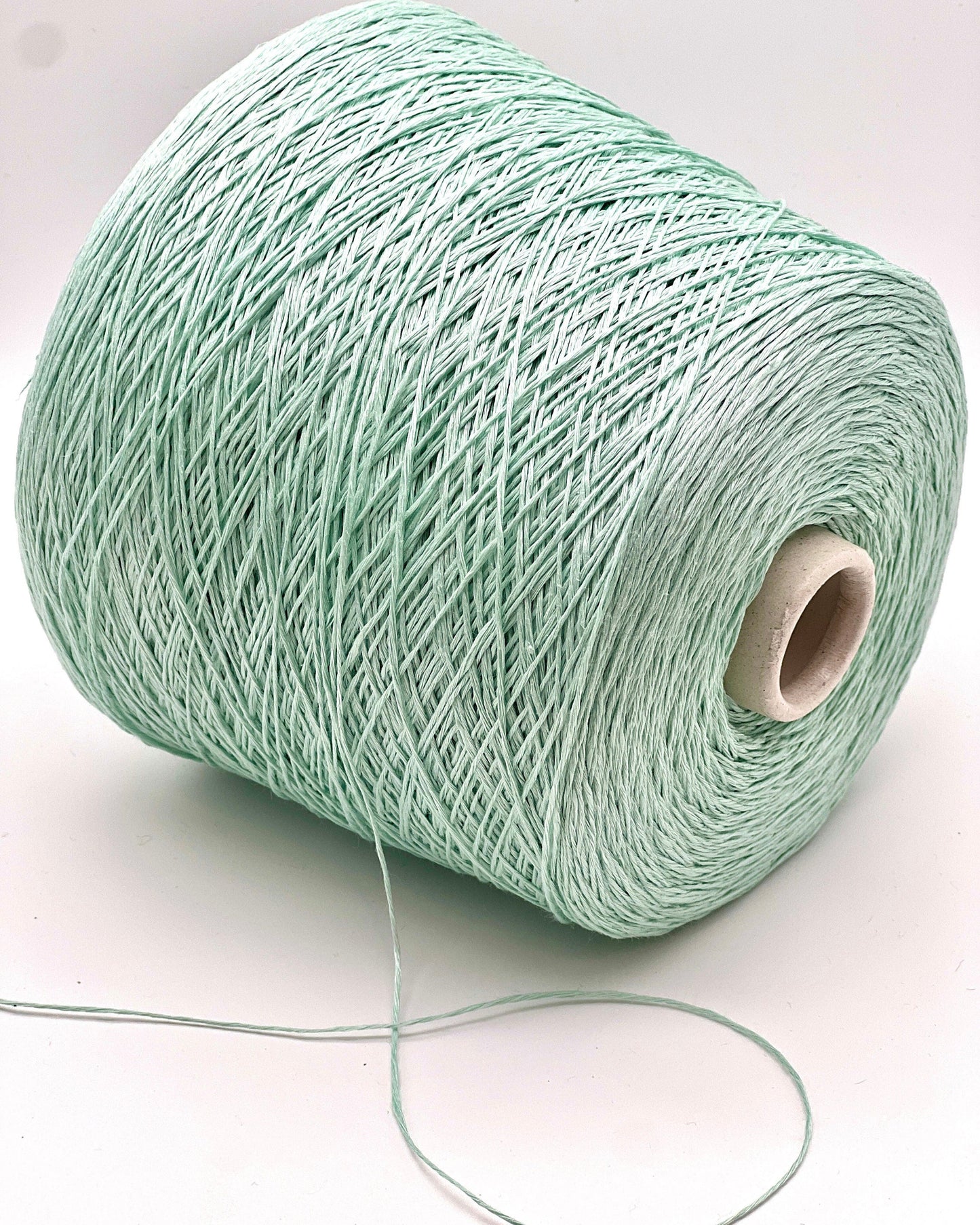 Spool of light green yarn on a white background