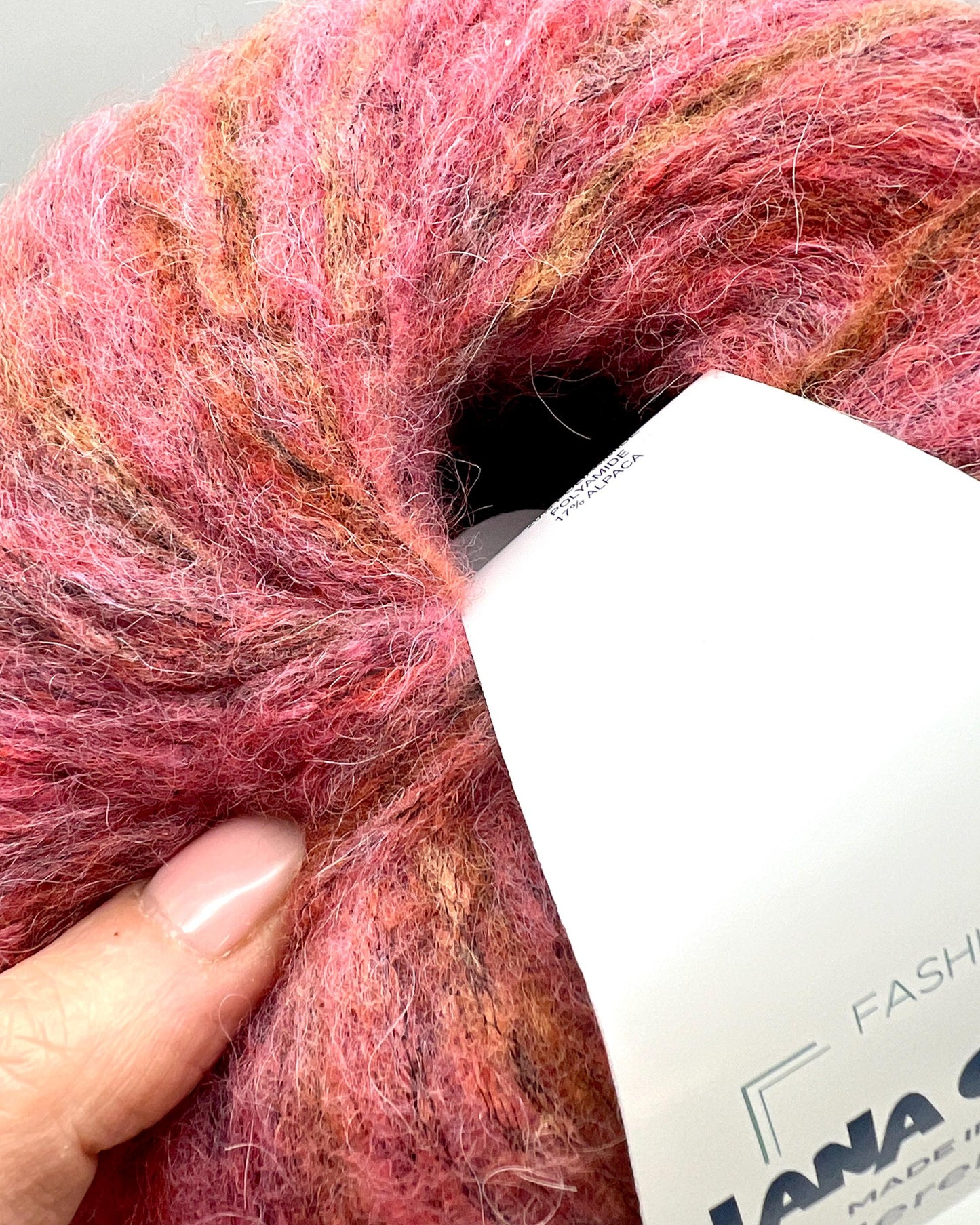Ball of pink yarn with a label on a light gray background