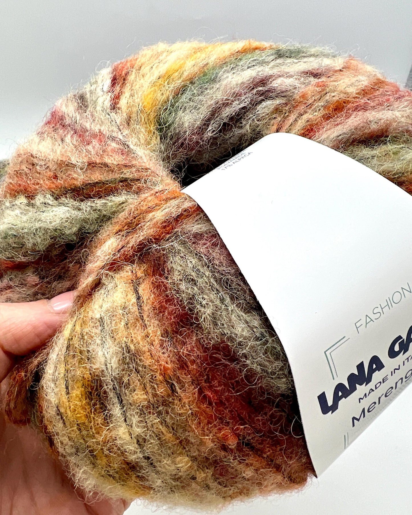 Multicolored skein of yarn with a label on a light gray background