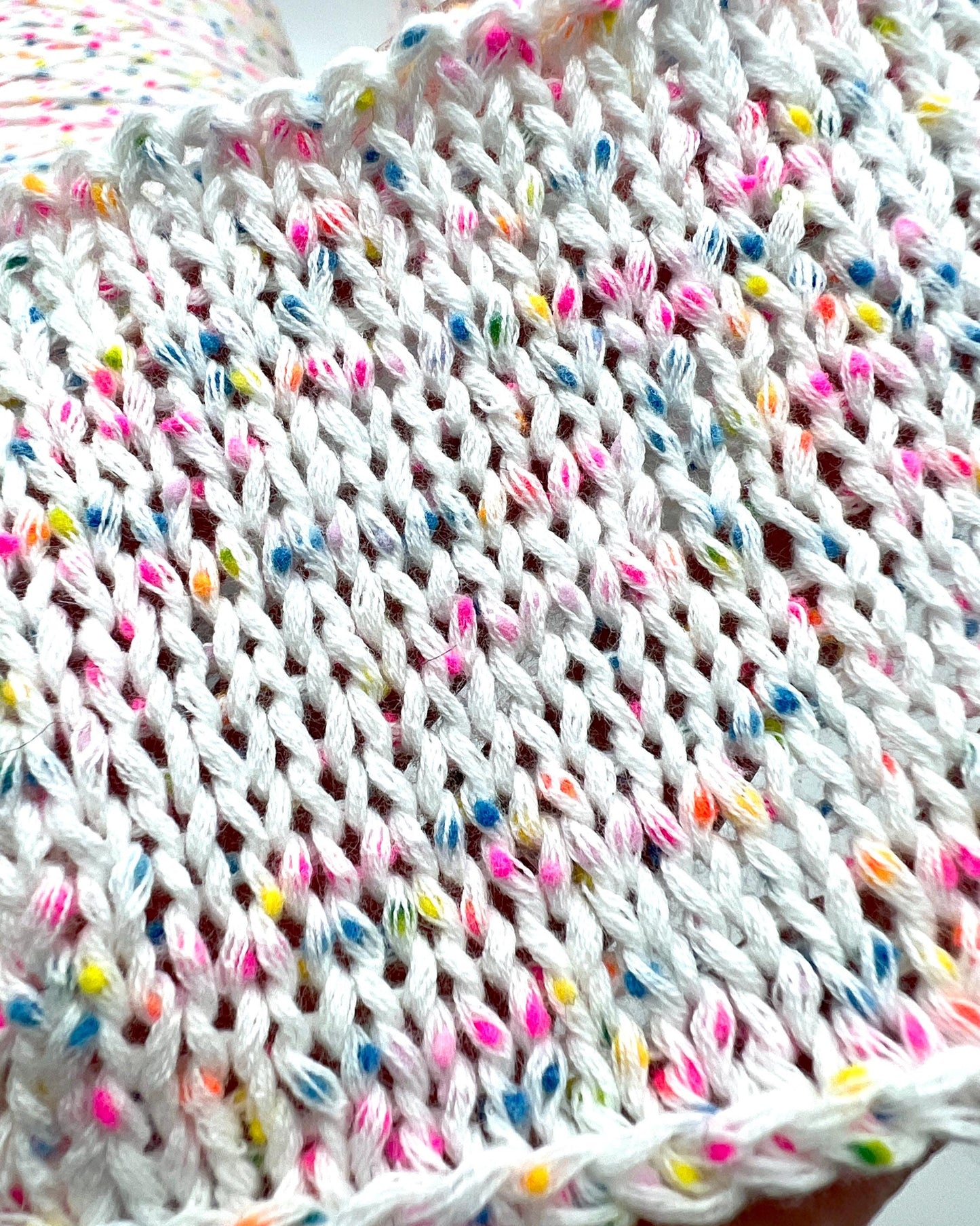 Close-up of a knitted fabric with colorful yarn strands.