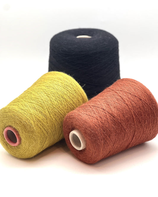 Three spools of yarn in black, yellow, and brown on a white background
