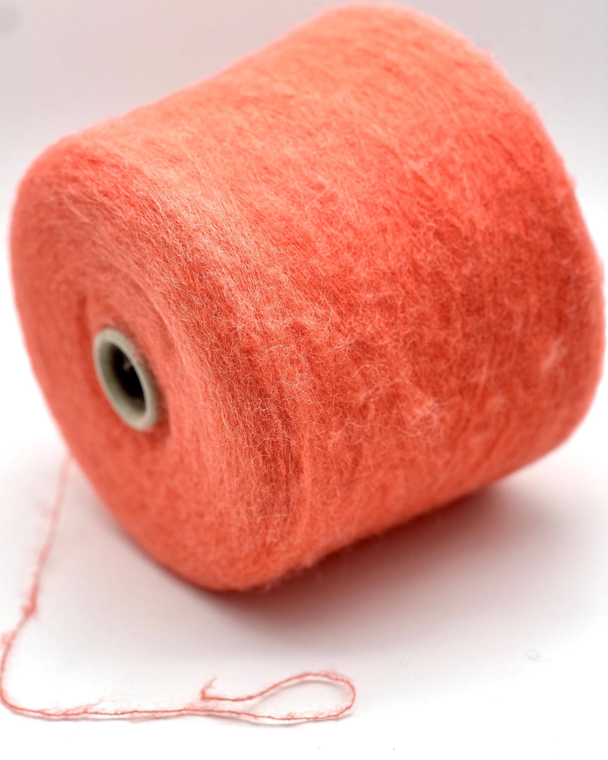 Spool of orange yarn on a white background