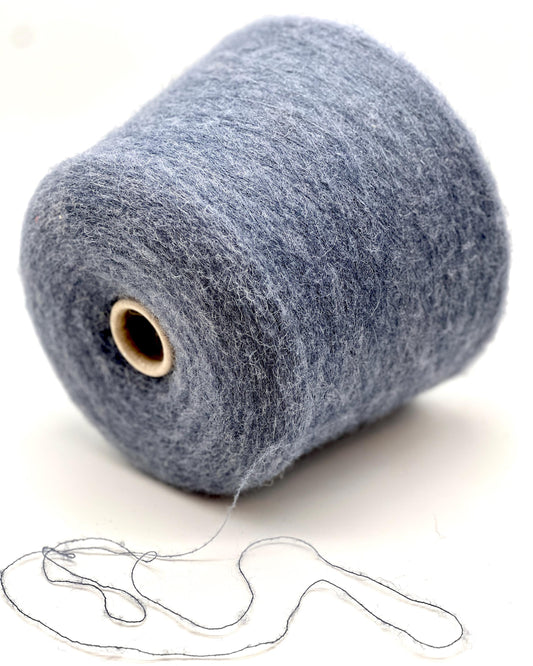 Large spool of gray yarn with a small amount of yarn extended on a white background