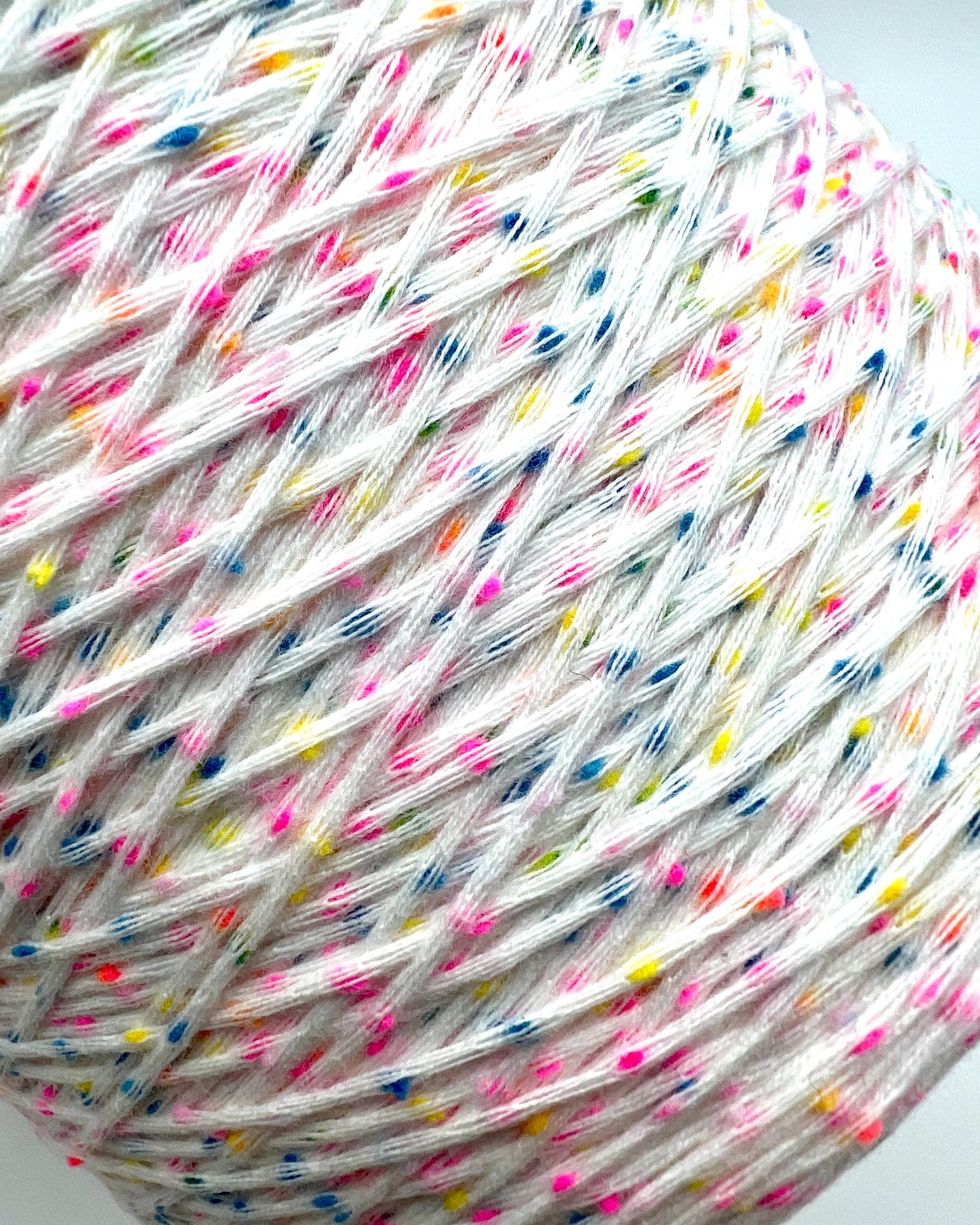Multicolored yarn ball with small specks on a white background