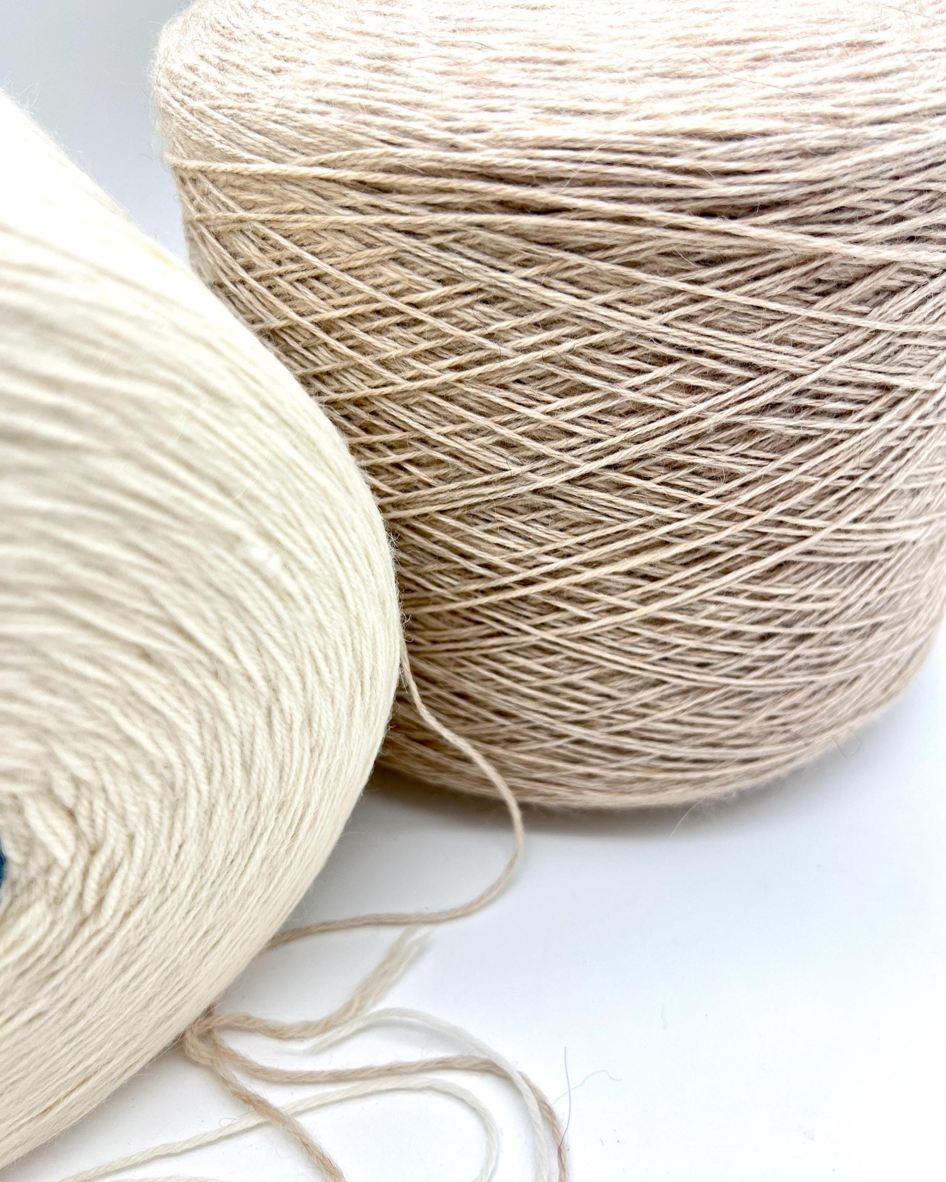 Two skeins of beige yarn on a white surface