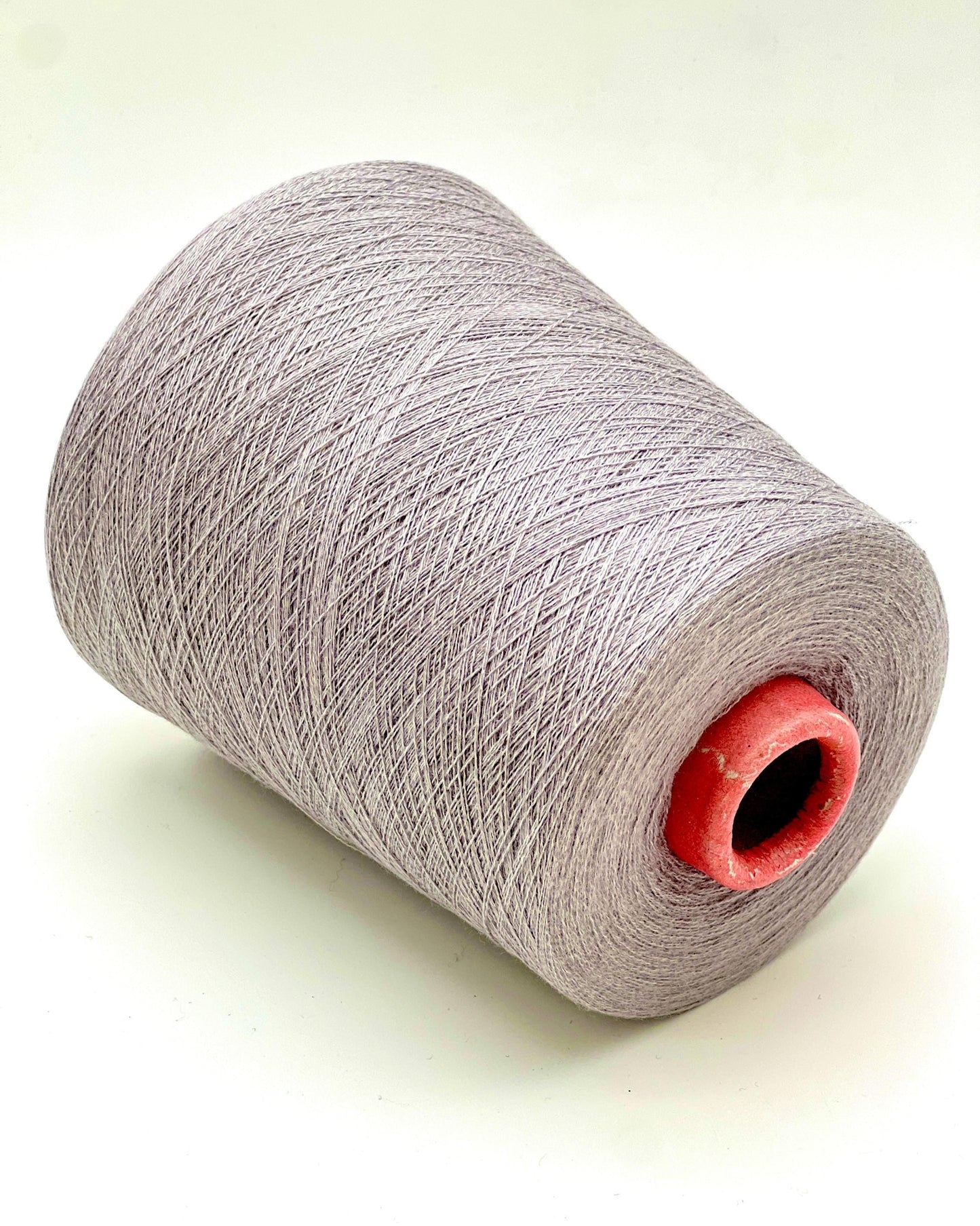 Spool of gray yarn with a red core on a light background