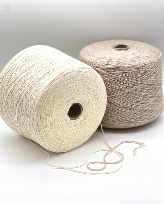 Two spools of yarn, one white and one beige, on a light background