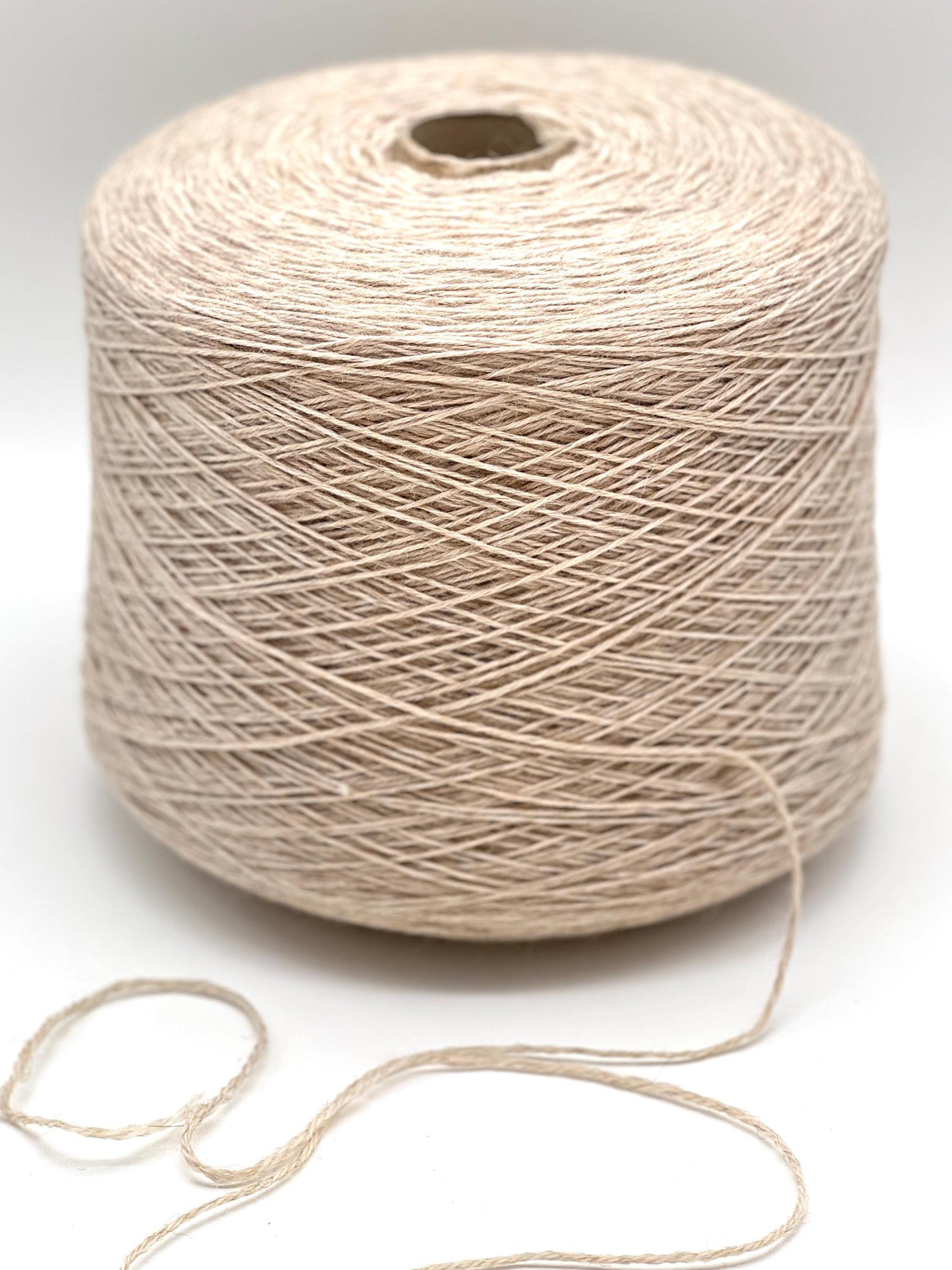 Spool of beige yarn on a white background