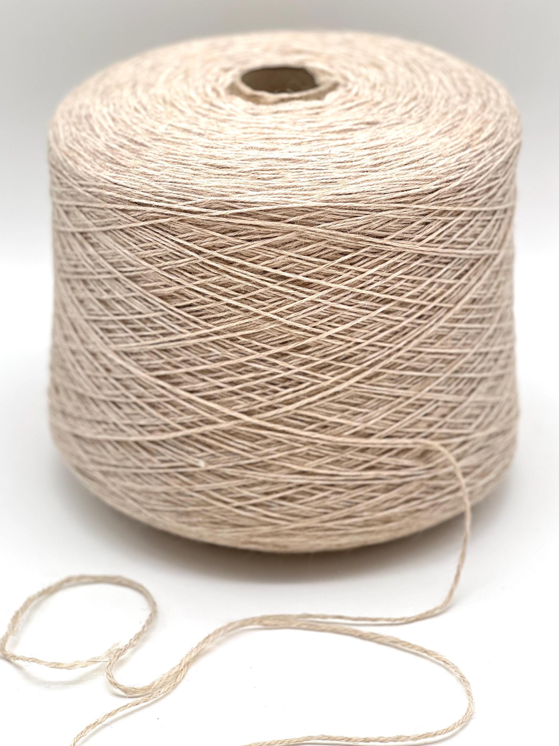 Spool of beige yarn on a white background