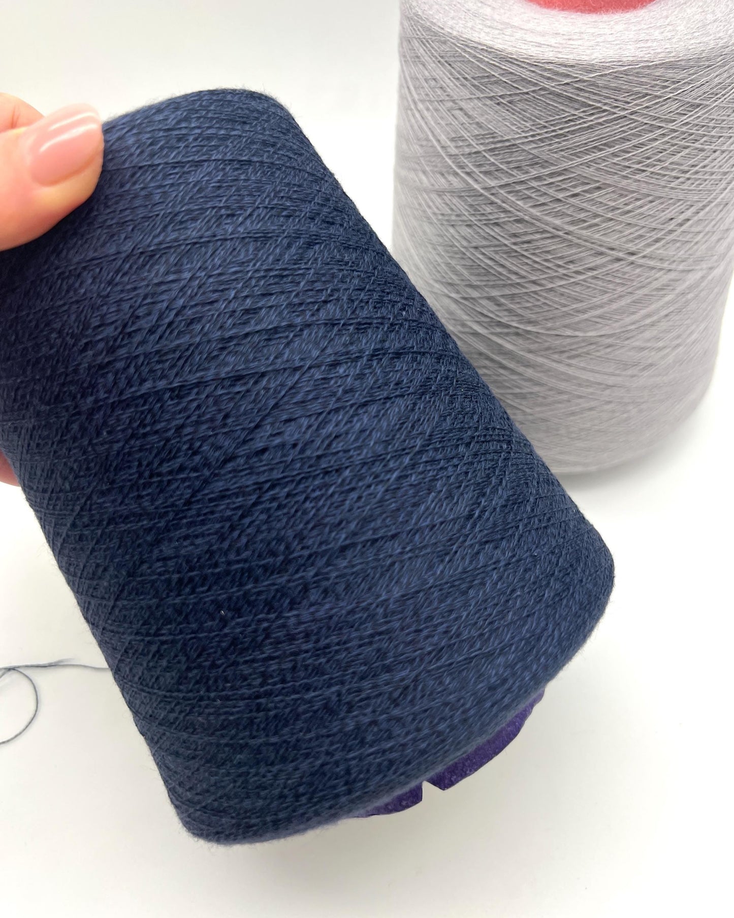 Two spools of yarn, one blue and one gray, on a white background.