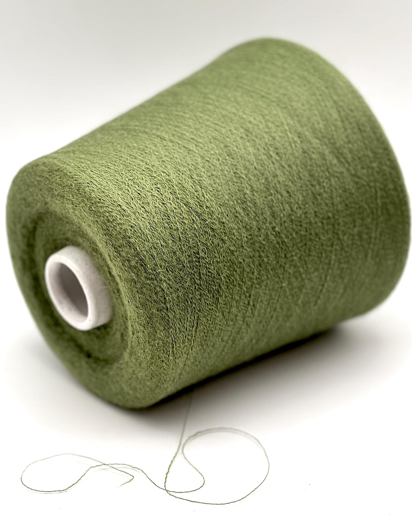 Green spool of thread on a white background