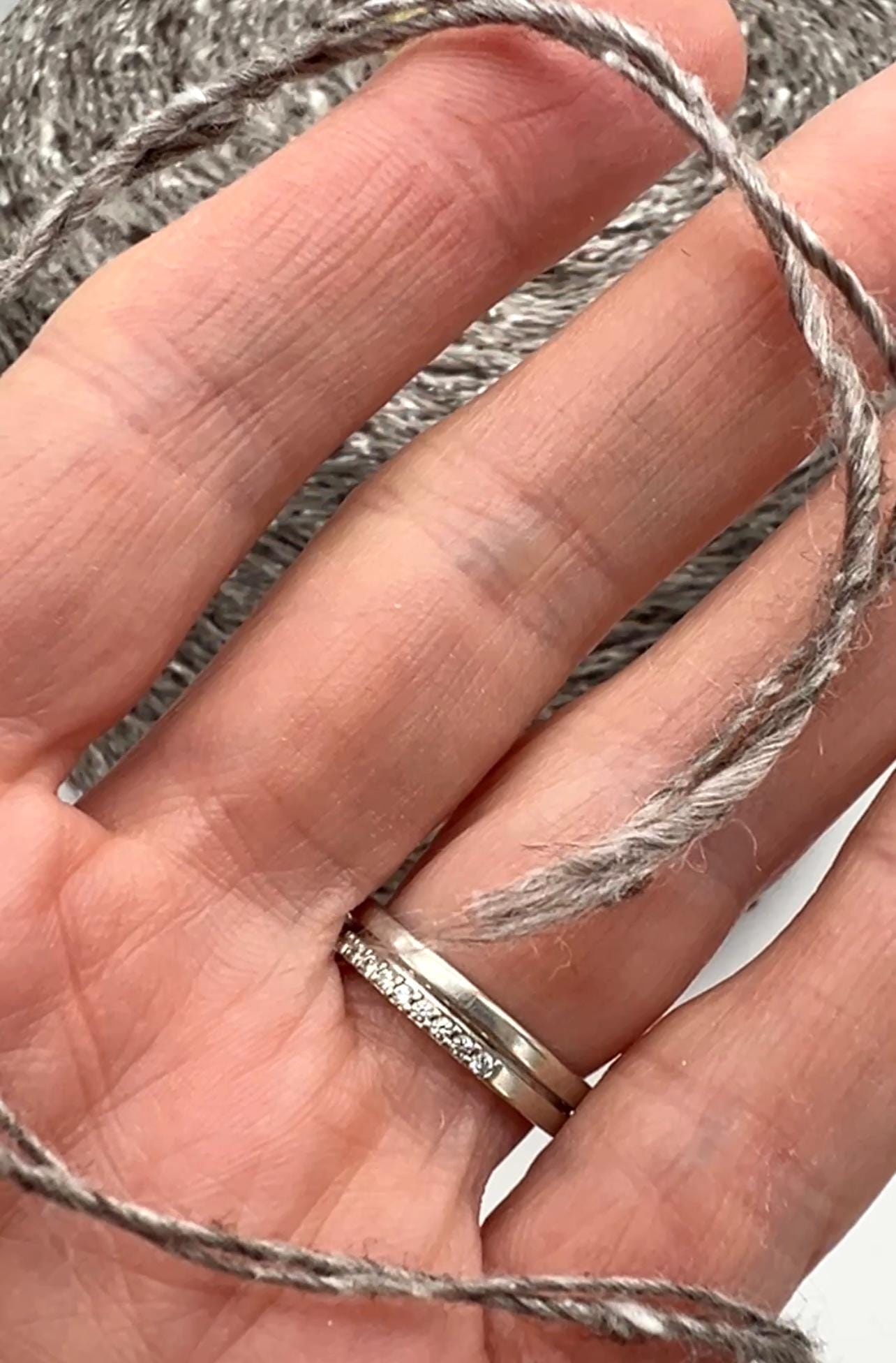 Silver ring on a hand with gray yarn