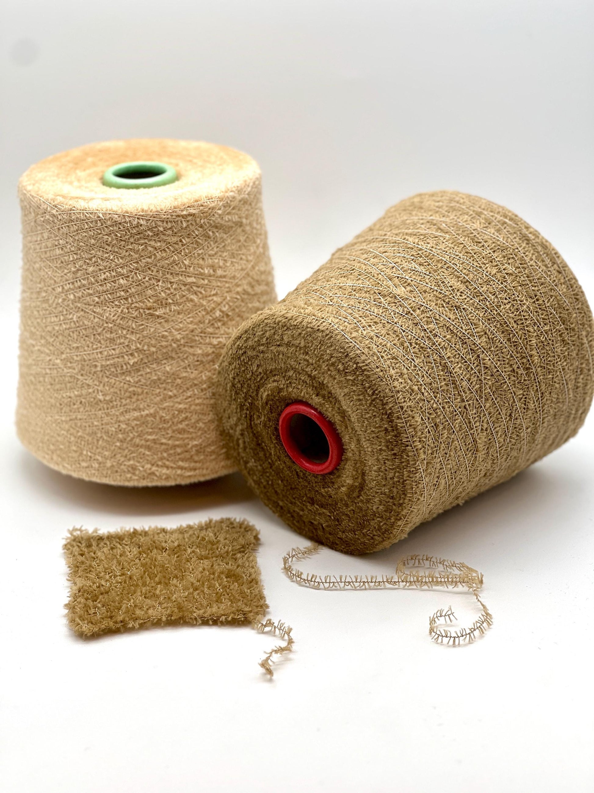 Two spools of beige yarn with a small swatch on a white background