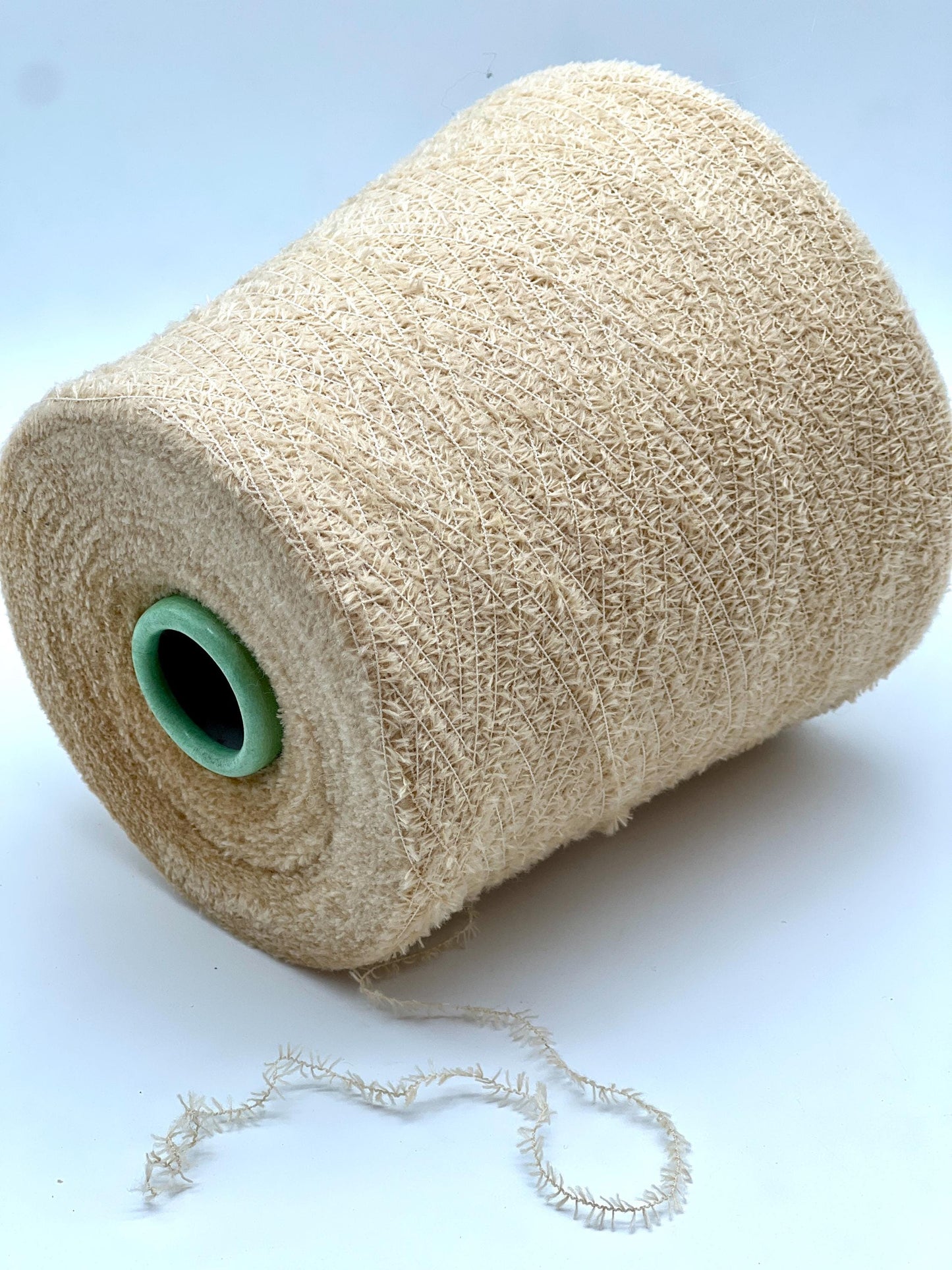 Spool of beige thread with a green core on a white background