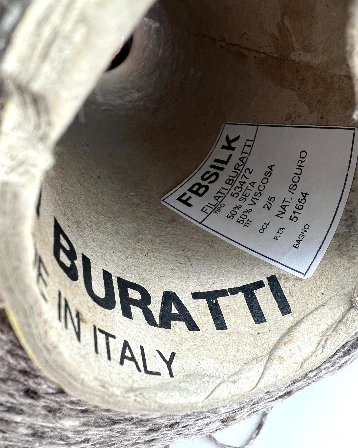 Close-up of Buratti fabric with a label on a textured background