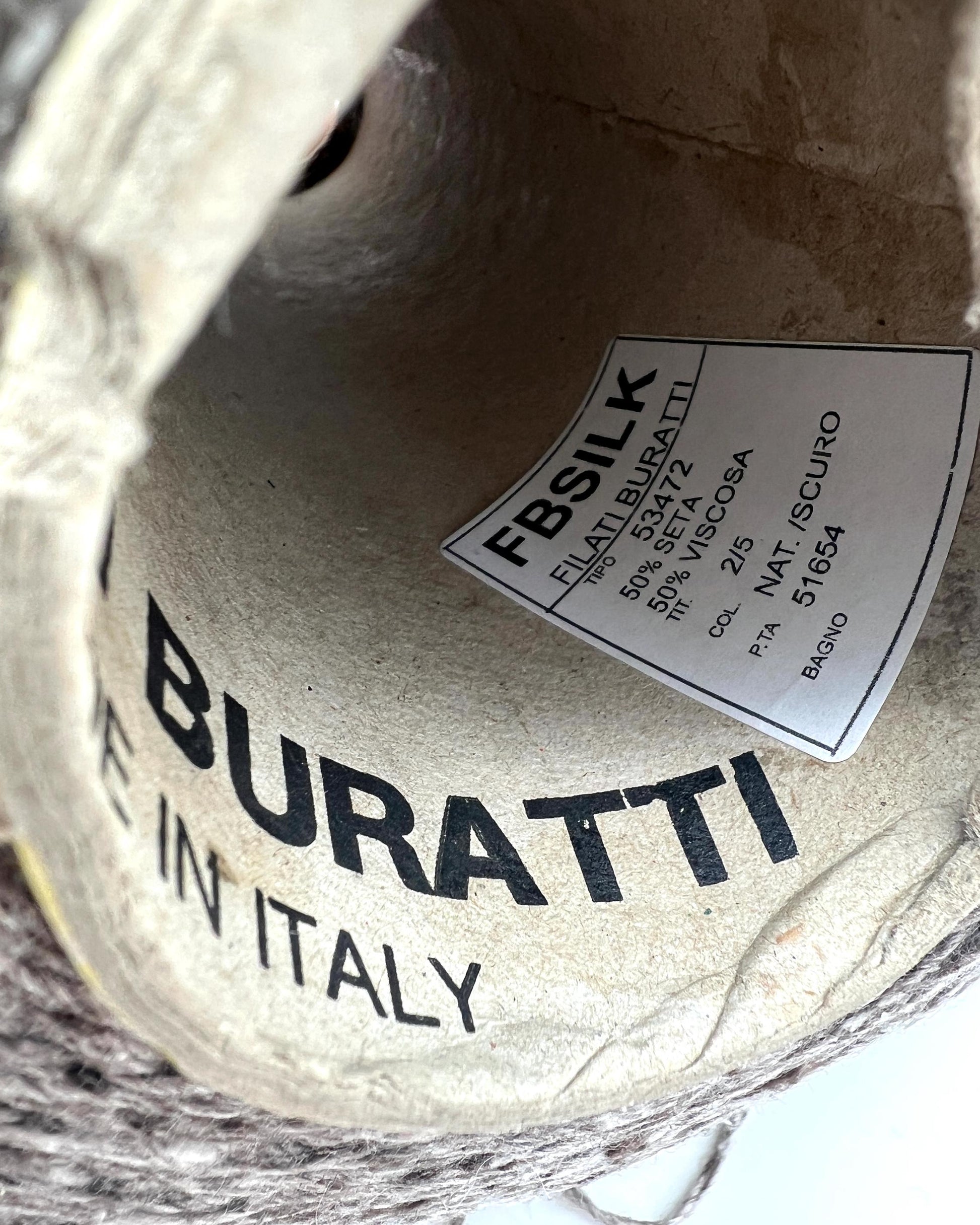 Close-up of Buratti fabric with a label on a textured background