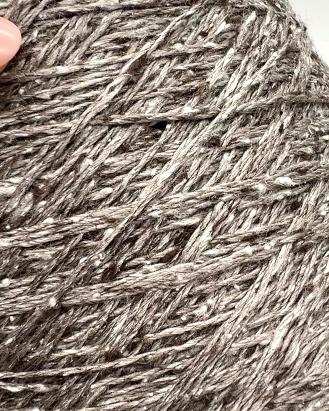 Close-up of gray yarn with a hand holding it