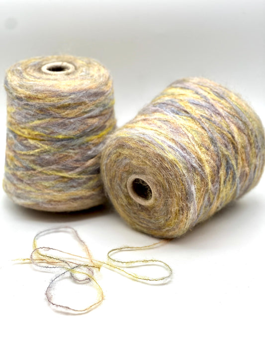 Two spools of gray and yellow yarn on a white background