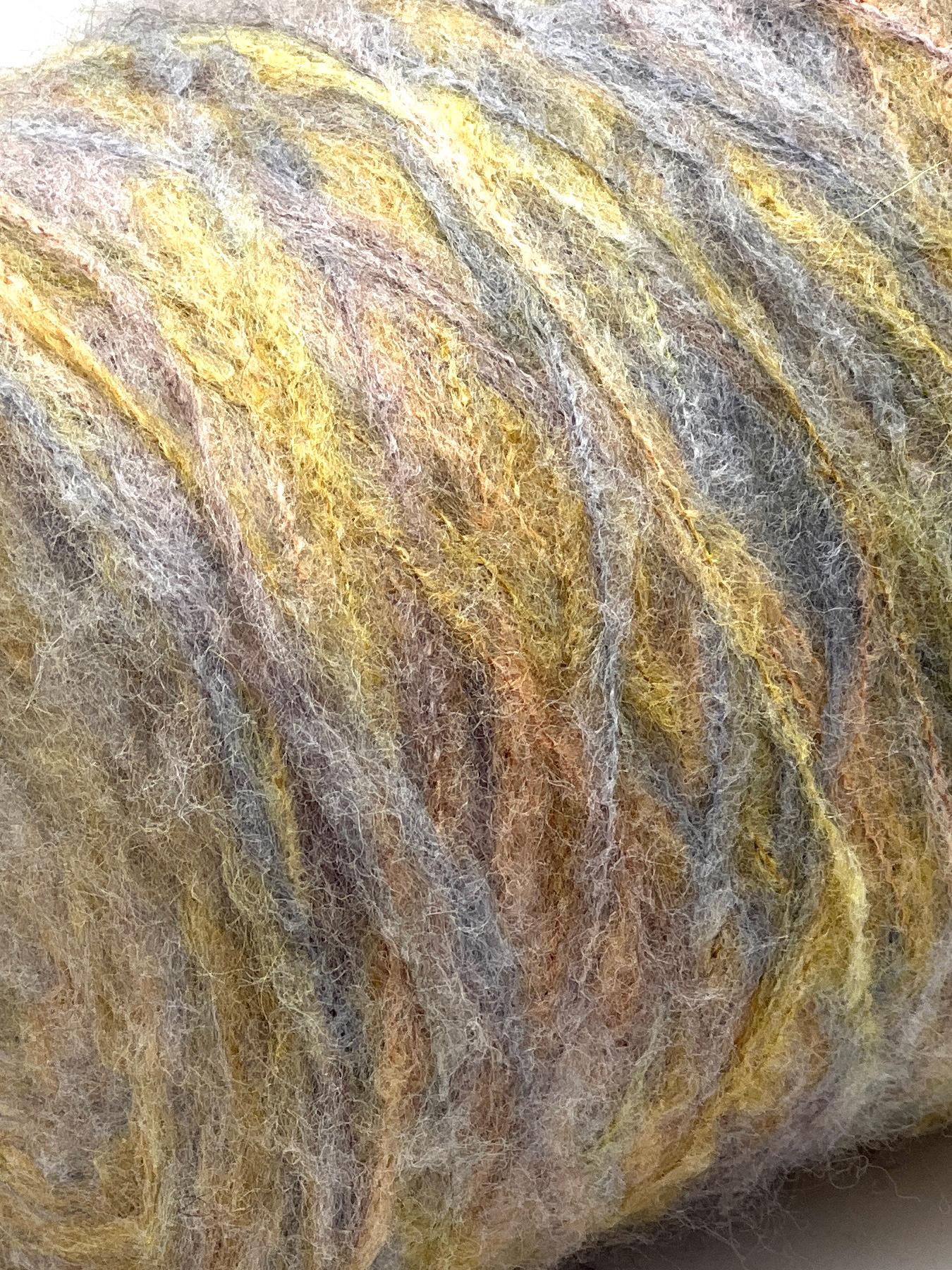 Close-up of a ball of multicolored yarn with shades of yellow, brown, and gray.
