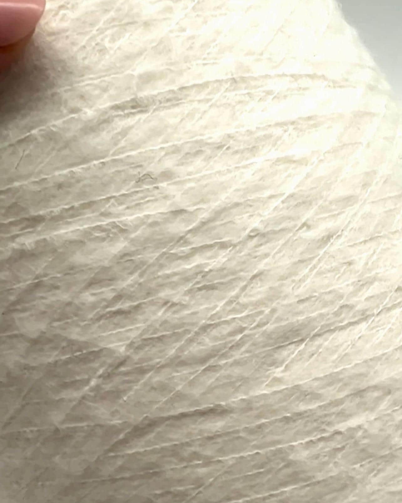 Close-up of textured white paper with a finger for scale