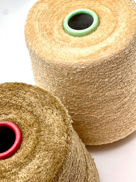Two spools of beige twine with red and green ends on a white background