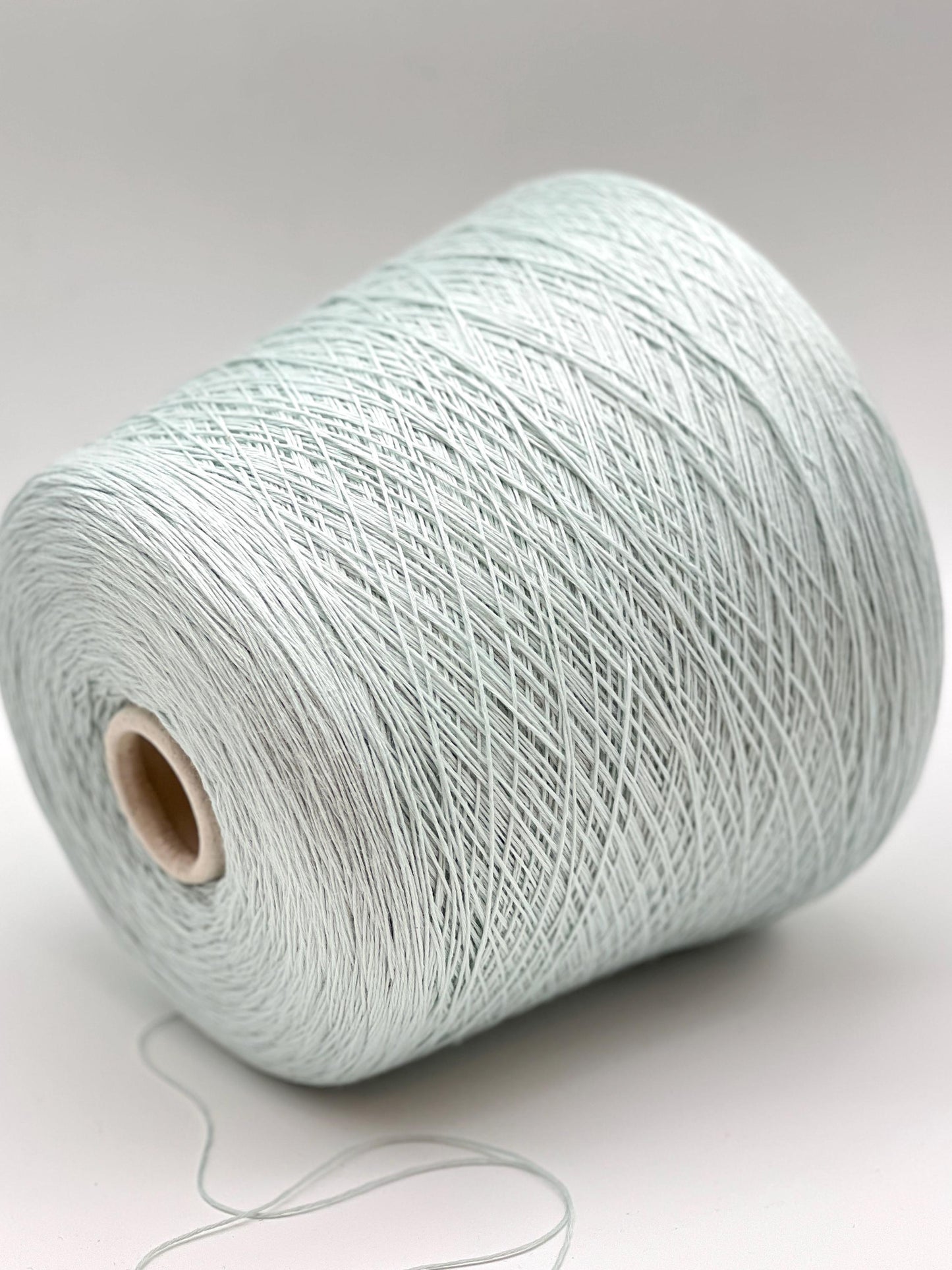 Spool of light blue yarn on a white background