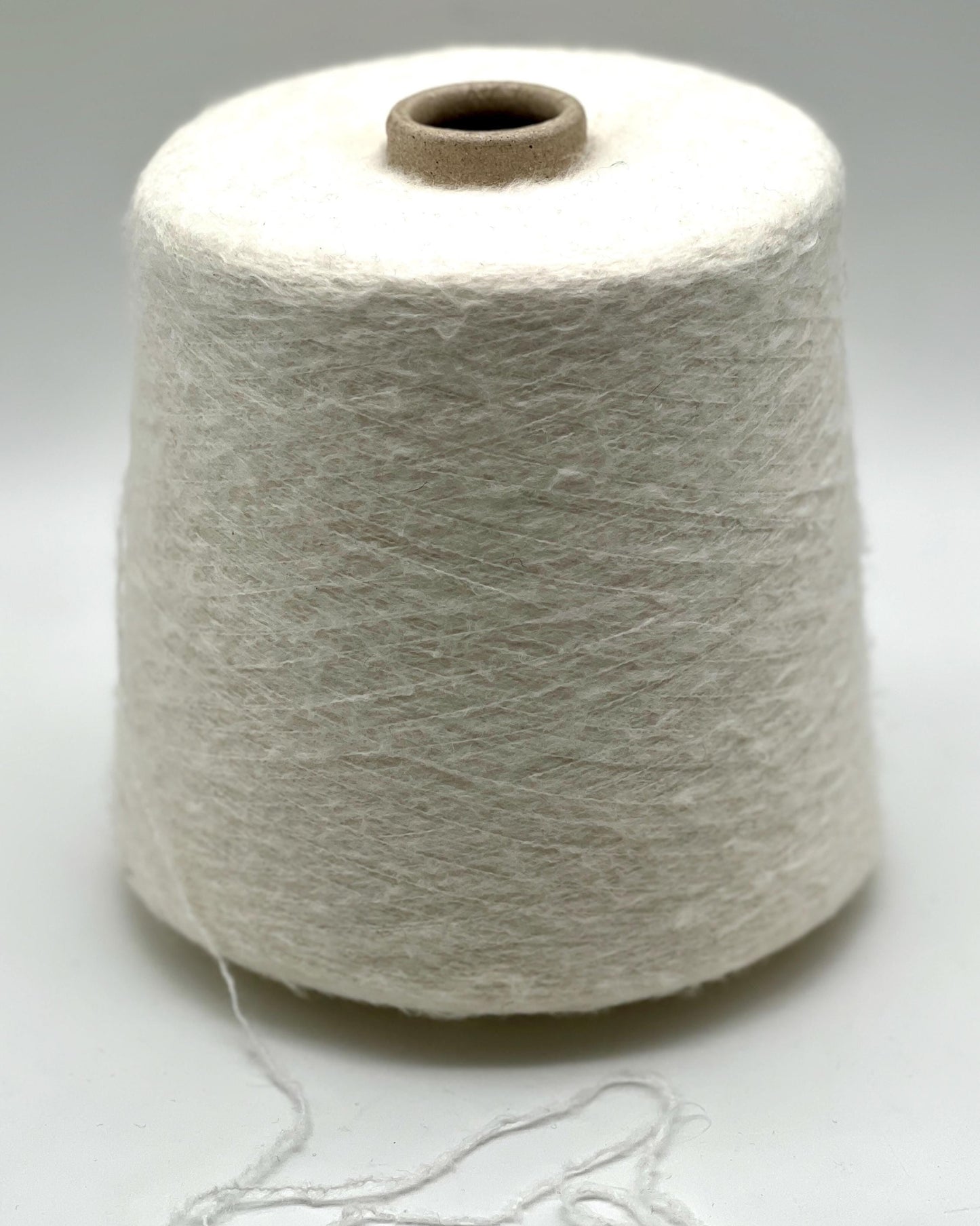 Spool of white yarn on a light gray background