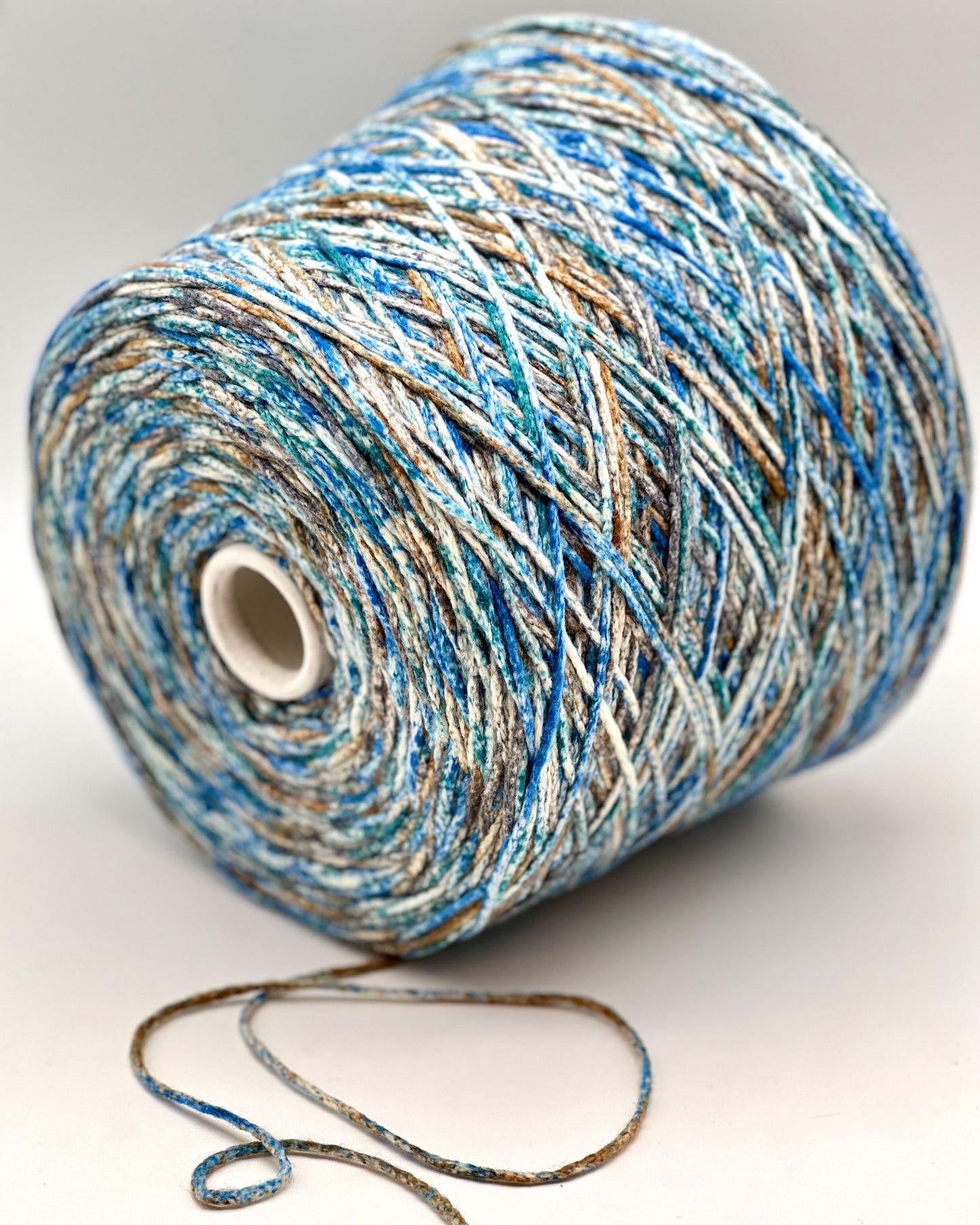 Spool of blue and beige yarn on a white background