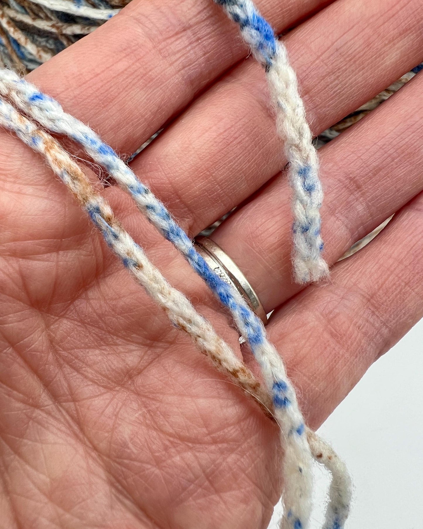 Close-up of a hand holding a piece of multicolored string.