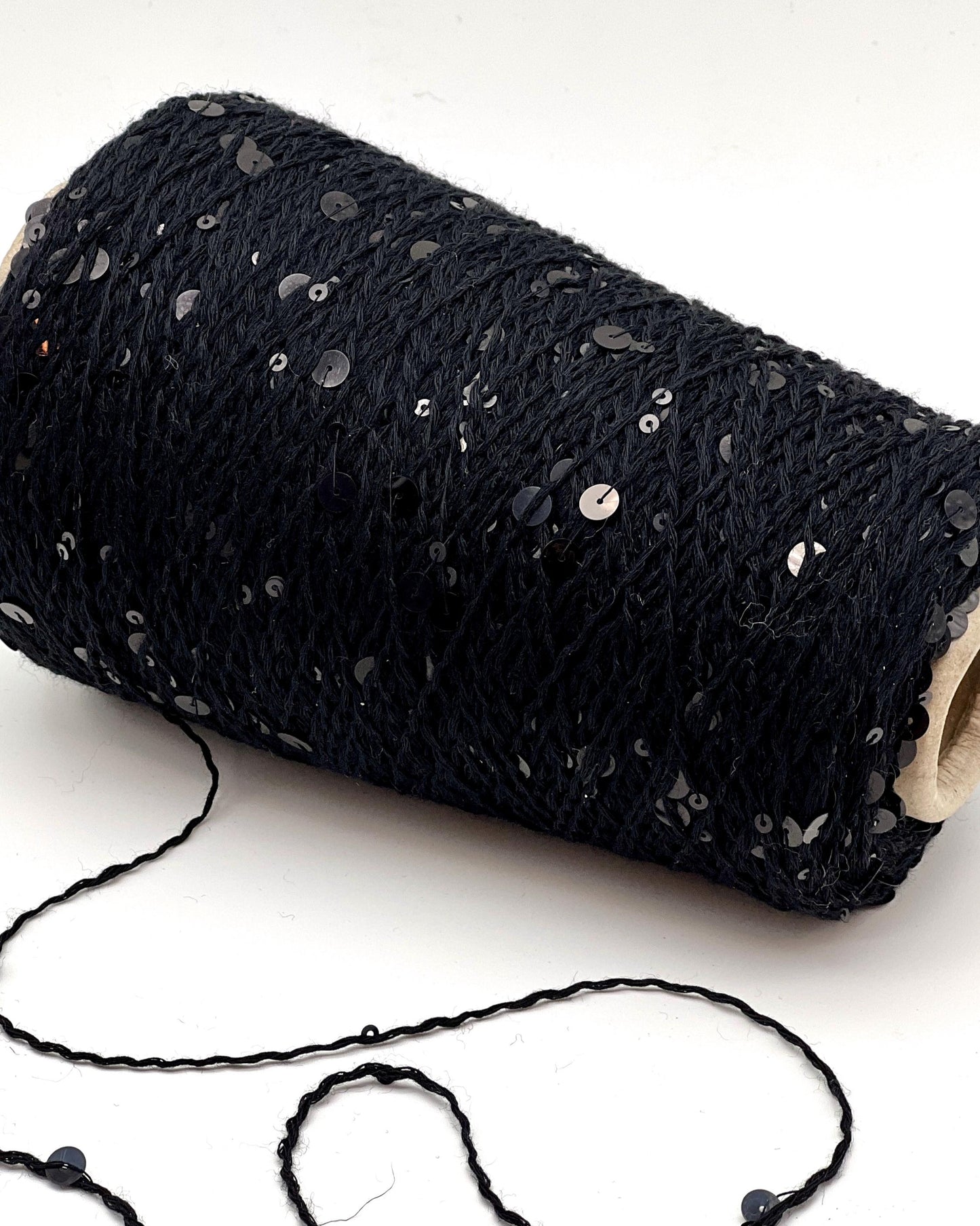 Roll of black yarn with sequins on a white background