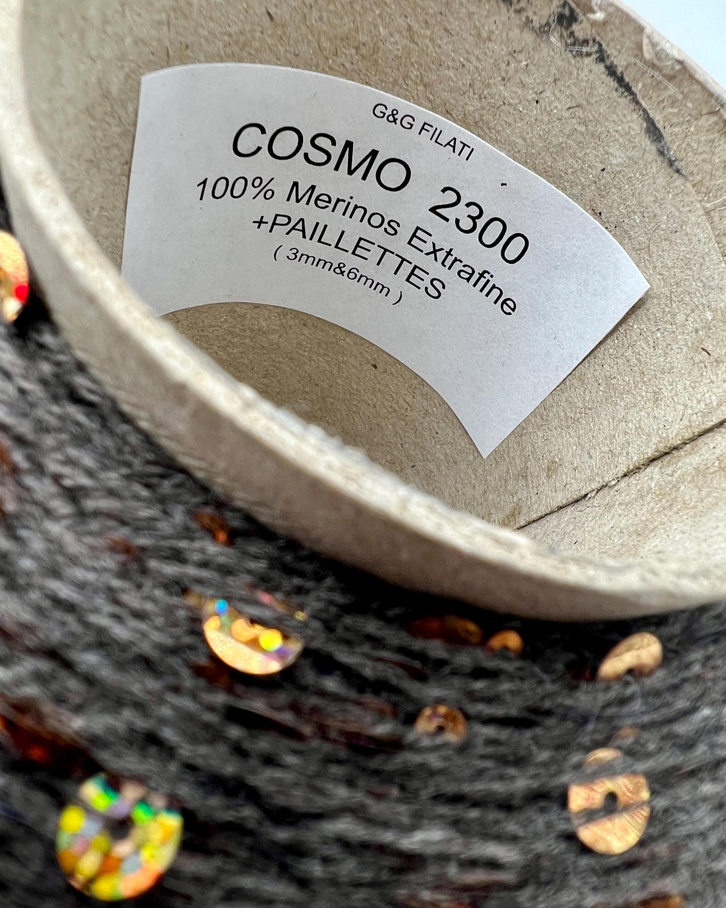 Close-up of a yarn ball with a label indicating 'COSMO 2300' and details about the yarn.