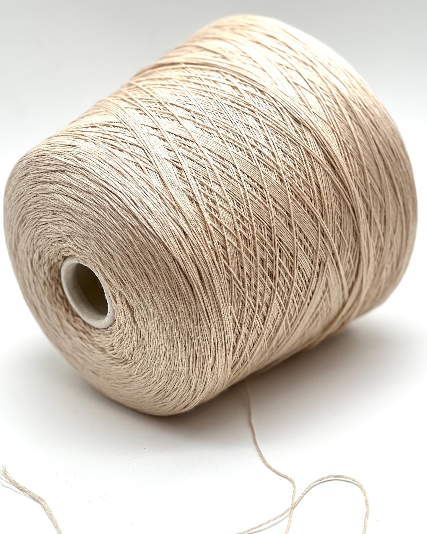 Spool of beige yarn on a white background