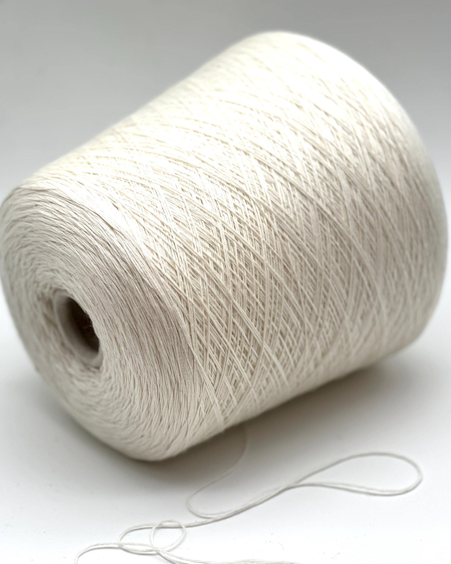 Spool of white yarn on a light gray background