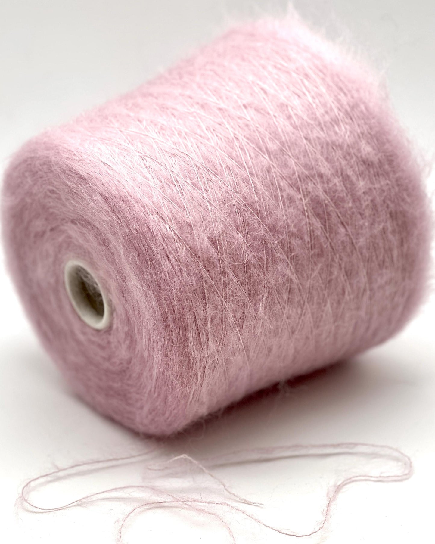 Pink yarn spool with a small ball of yarn on a white background
