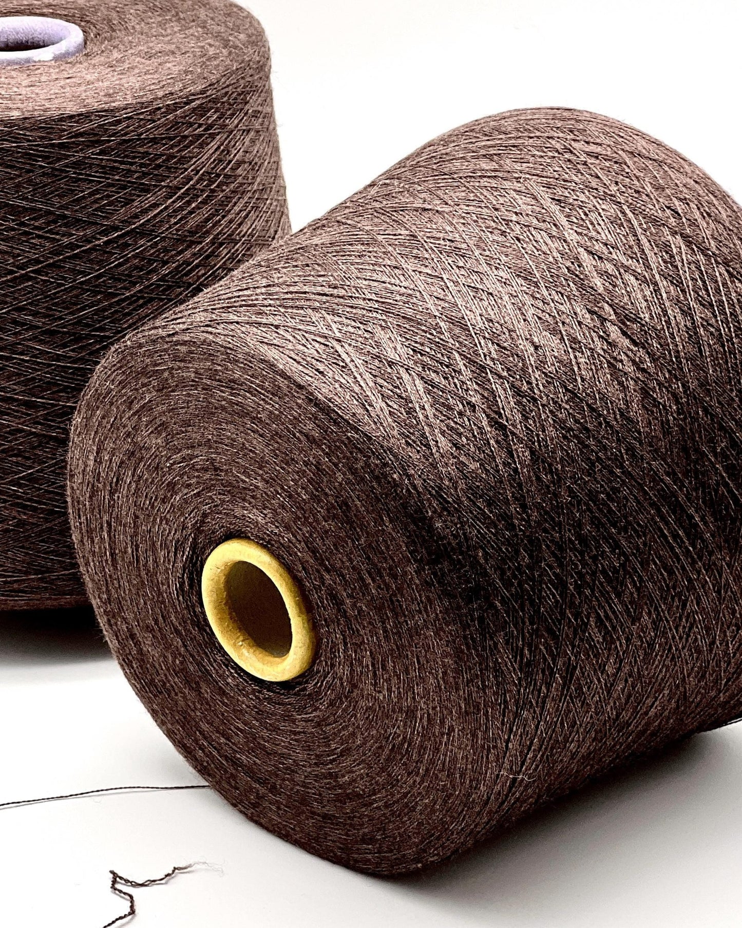 Two large spools of brown yarn on a white background