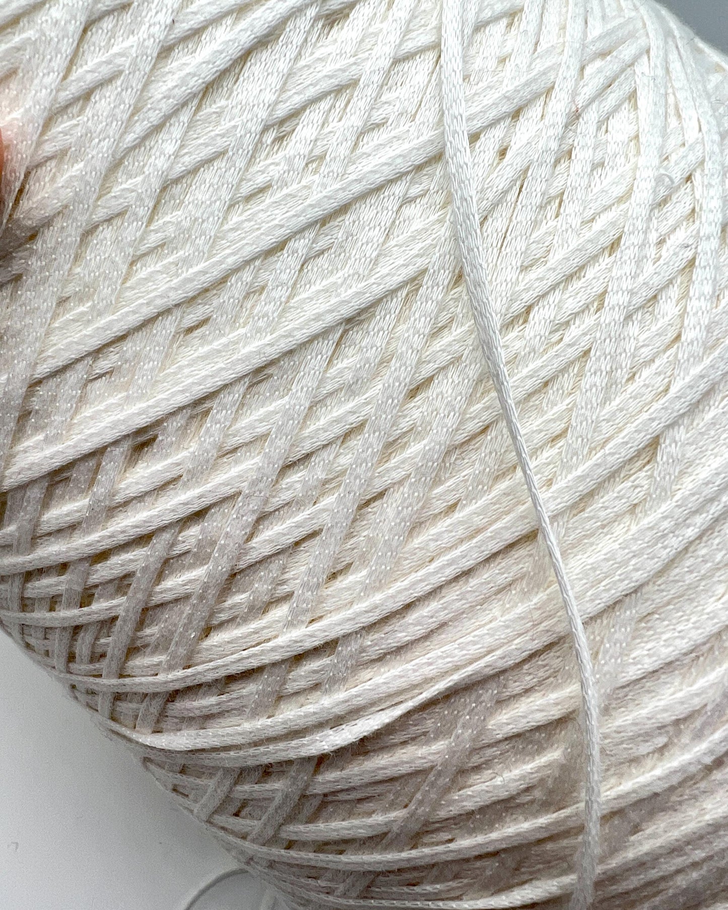 Close-up of a ball of white yarn on a light background