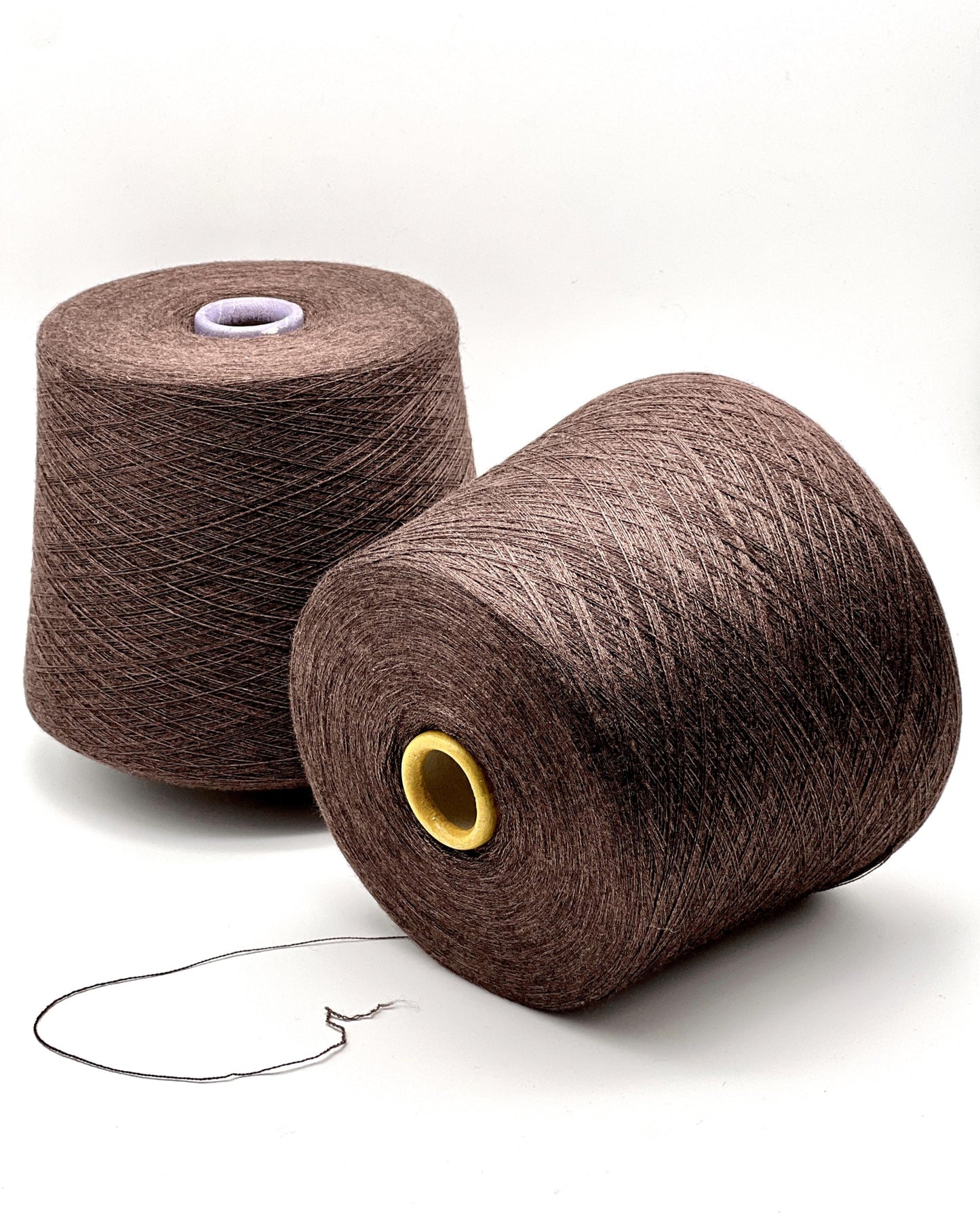 Two brown spools of yarn on a white background