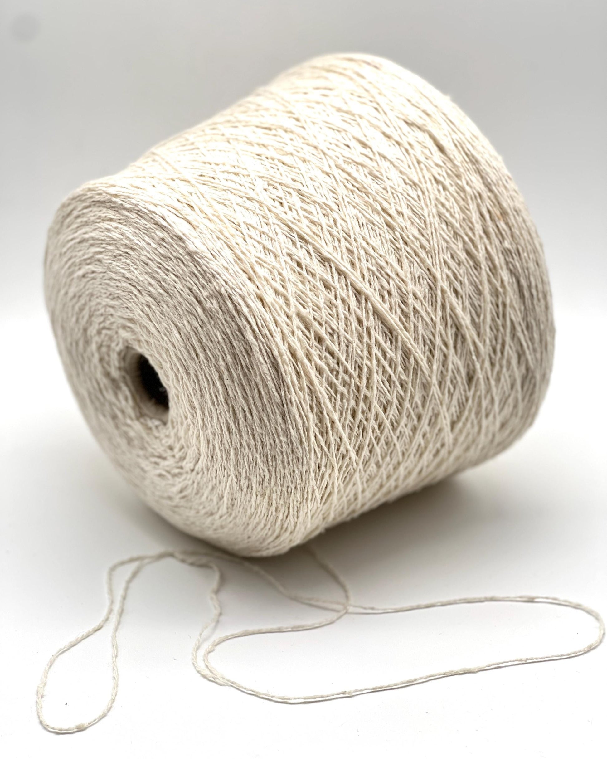 Spool of white yarn on a light gray background