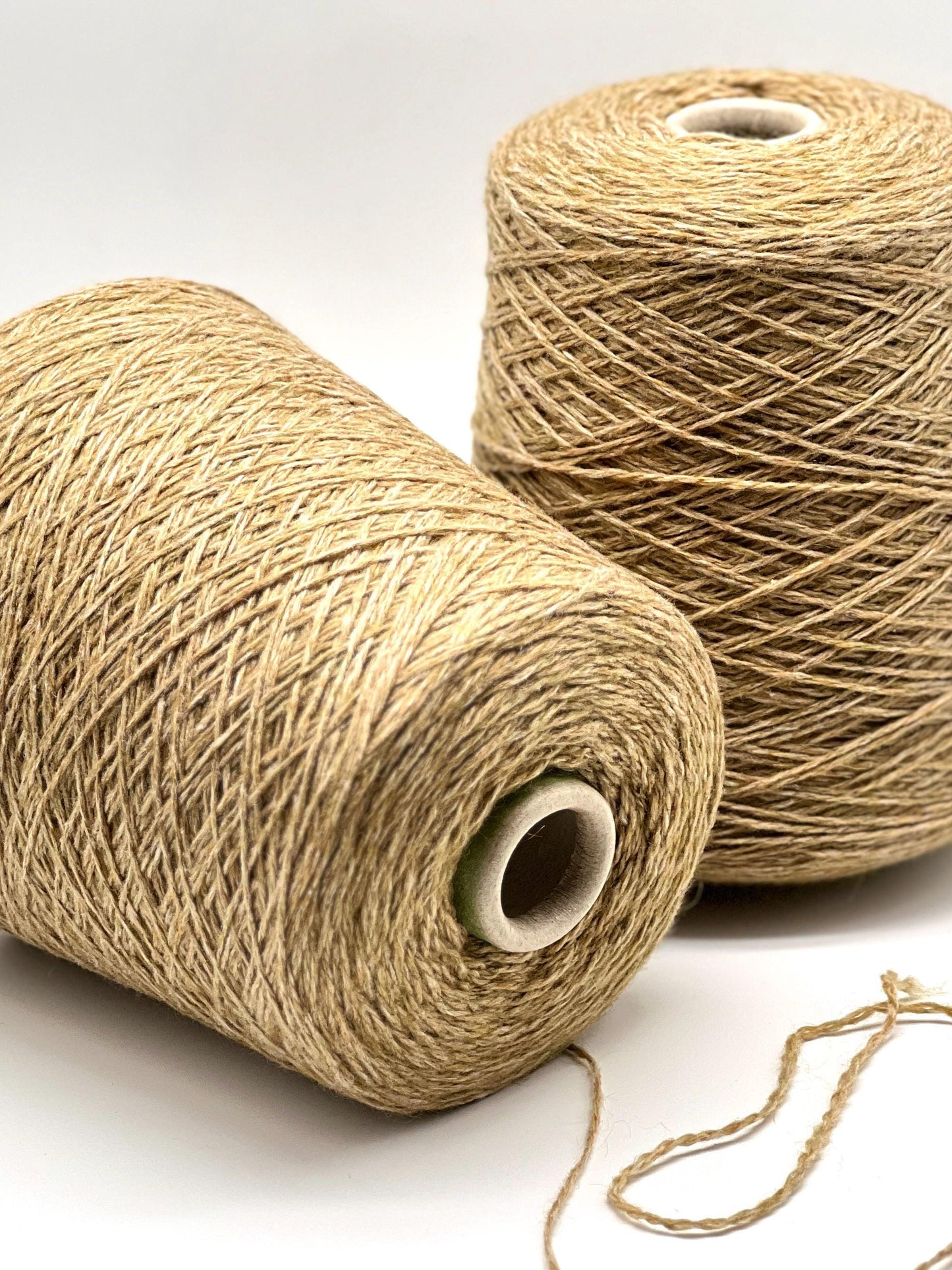 Two spools of beige thread on a white background
