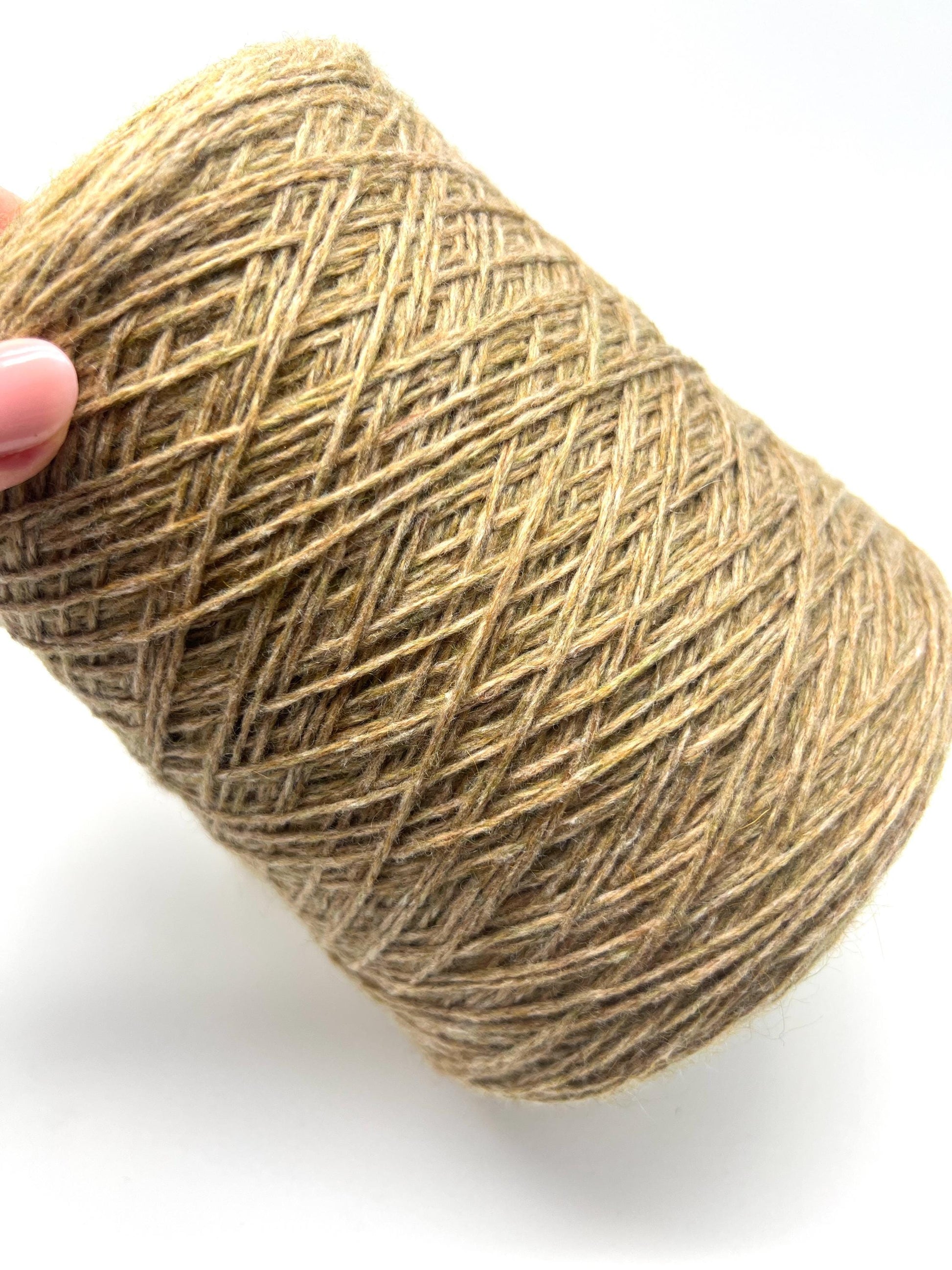 Ball of brown yarn held by a hand on a white background
